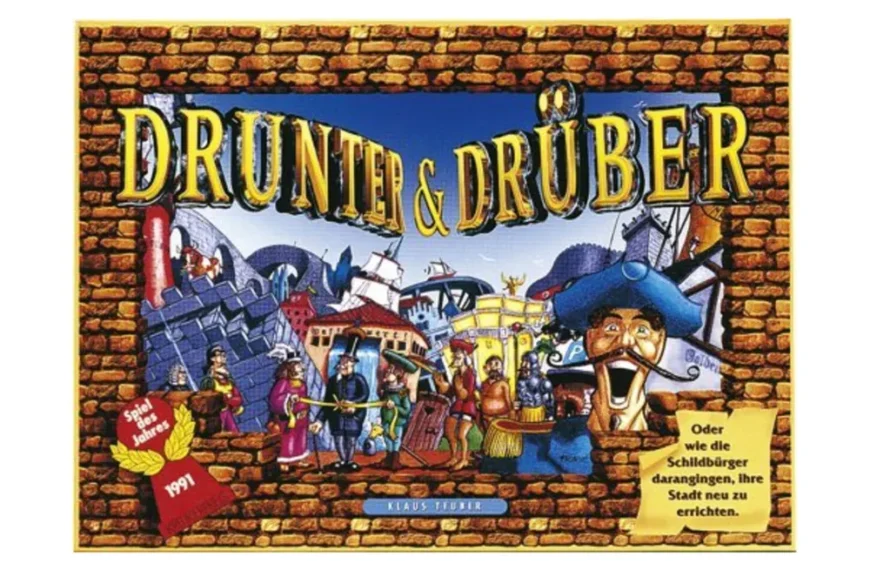 Box cover art for the board game "Drunter & Drüber" featuring colorful cartoon characters in an old European town setting, with brick borders and the game's title prominently displayed in the center.