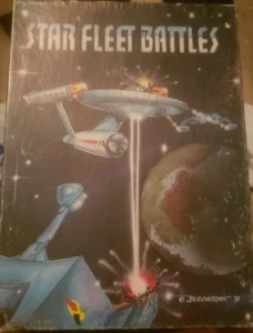 A worn cover of the "Star Fleet Battles" game, featuring artistic space battle illustrations with spaceships and explosions against a starry background.