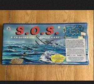 An image of the board game "S.O.S.: A CO-OPERATIVE RESCUE GAME" box on a wooden surface. The box art illustrates a dramatic sea rescue scene with waves, people in the water, and helicopters above. There are texts detailing the game's contents, age suitability, and number of players.