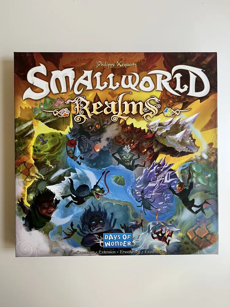 Box front cover of "Small World Realms" board game by Days of Wonder featuring colorful fantasy artwork with various mythical creatures and characters.