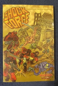 A paperback book cover for "Shock Force: Science Fiction Miniature Wargaming" featuring stylized artwork of futuristic soldiers in battle with alien creatures. The title is in bold, 3D-effect letters at the top, and the "DemonBlade Games" logo is at the bottom. The illustration depicts abstract destruction and combat with a reddish and yellow color palette.