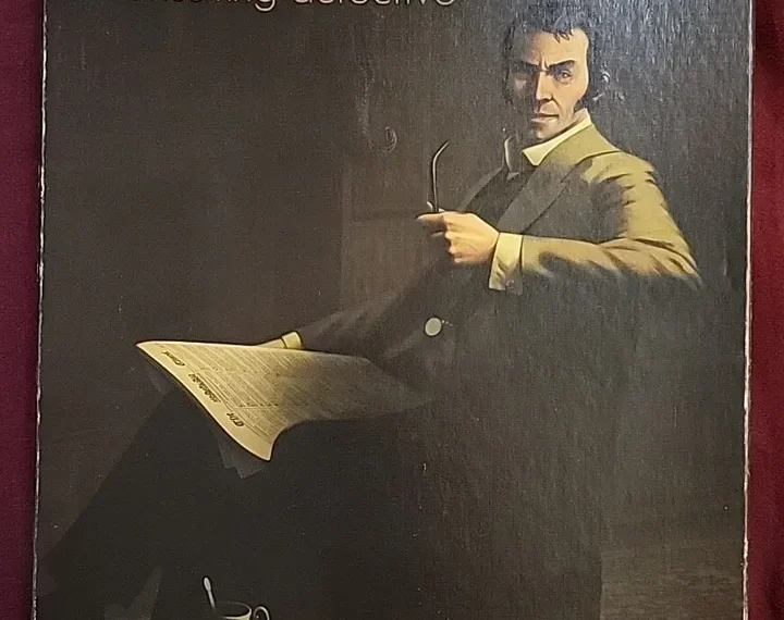 An illustrated game cover portraying Sherlock Holmes as a consulting detective with a pipe in his hand, alongside items such as papers, a magnifying glass, and a cup of tea, with the logo of Ystari Games at the bottom.