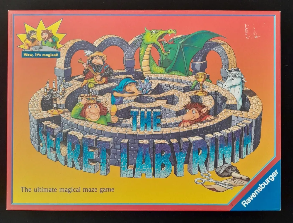 A board game cover titled "THE SECRET LABYRINTH" with illustrated fantasy characters, including a green dragon and various whimsical creatures in a maze, with the tagline "The ultimate magical maze game" and the logo of Ravensburger in the bottom right corner.
