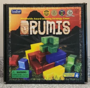Box cover of the "RUMIS" board game featuring colorful 3D brick shapes, an image of a stone head statue, and multiple award badges, with a warning label for small parts and a logo of Educational Insights.