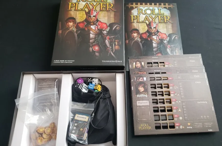 An open box of the Roll Player board game with its components partially unpacked on a table, including dice in a black bag, cards, and character sheets, with the game's box cover visible in the background.