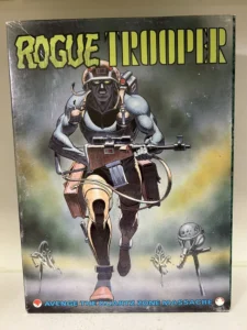 Comic book cover of "ROGUE TROOPER" featuring a futuristic soldier running towards the viewer with a rifle in hand, wearing a helmet with goggles and a backpack with antenna, set against a foggy battlefield background with skeletal remains and the tagline "AVENGE THE QUARTZ ZONE MASSACRE" at the bottom.