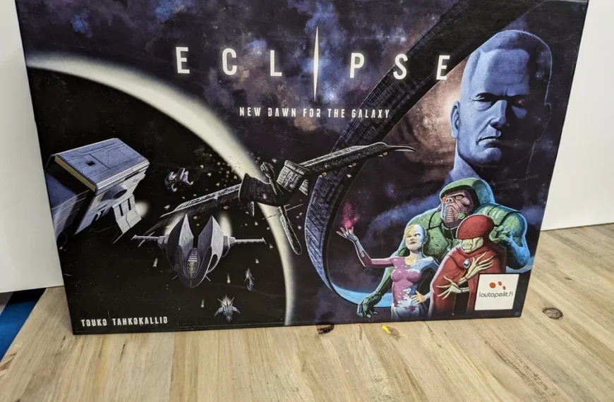 The image shows a board game box for "Eclipse: New Dawn for the Galaxy" featuring artwork with spaceships, a planet, an eclipse, and illustrated characters that appear to be spacefarers or aliens. There is text stating the designer's name, Touko Tahkokallio, and the publisher Lautapelit.fi's logo at the bottom. The box is positioned on a wooden surface against a white backdrop.