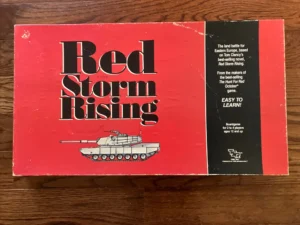 A tabletop board game box, "Red Storm Rising," with a red and black color scheme featuring an image of a tank on its cover, referencing Tom Clancy's novel and stating it's easy to learn for 2 to 4 players ages 12 and up.
