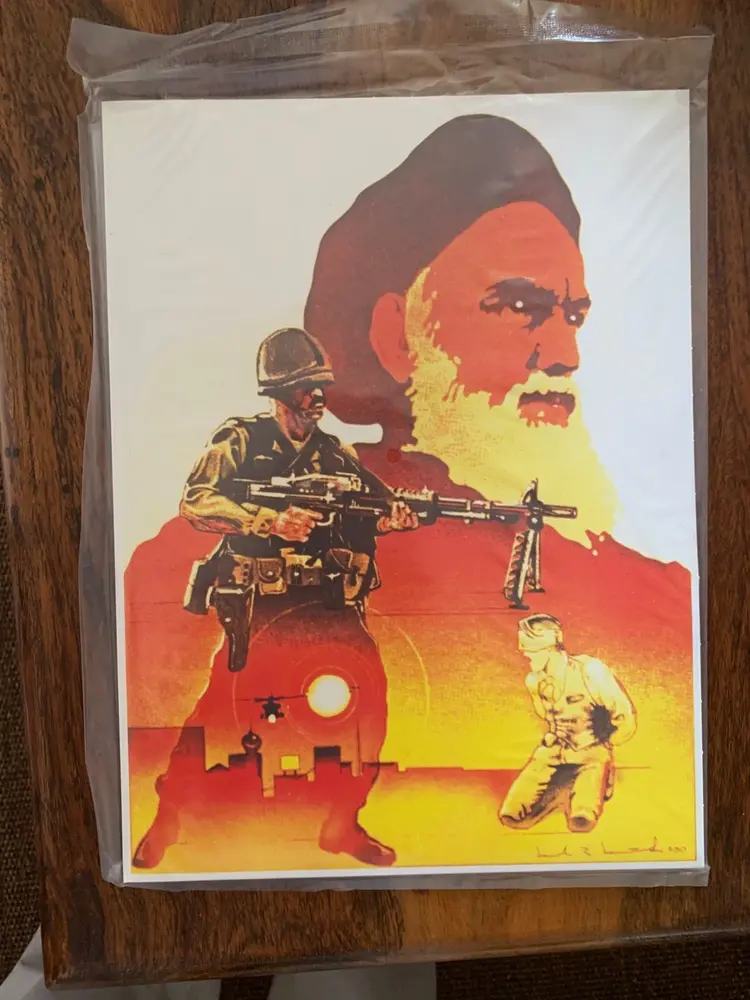 An illustration featuring a large profile of a bearded man in the background with a soldier wielding a gun in the foreground on the left and another figure kneeling on the right, set against an orange backdrop with a silhouette of a city skyline and the sun. The print is packaged in a clear protective sleeve, placed against a wooden surface.