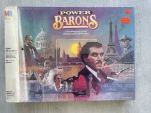 A board game called "Power Barons" by Milton Bradley, featuring illustrations of various people and iconic landmarks like the US Capitol and Eiffel Tower, designed for ages 10 to adult and 3 or 4 players, with a price sticker on the top right corner.