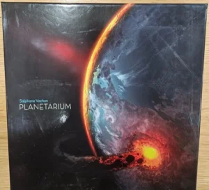 The image shows a book cover with a cosmic illustration of a planet partially engulfed in flames, with another fiery object and debris colliding into the planet's surface. The text "Stéphane Vachon PLANETARIUM" is displayed in the lower left corner.