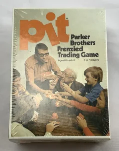 A shrink-wrapped vintage "Pit" card game box by Parker Brothers showing a depiction of a family excitedly playing the game. The game is for ages 8 to adult and accommodates 3 to 7 players.