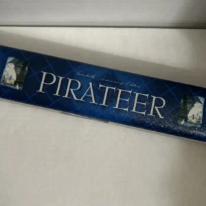 A side view of a board game box with the title "PIRATEER" in large white letters, labeled as the "Immortal 20th Anniversary Edition," with a blue background and illustrations of sailing ships at both ends.