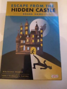 A board game cover titled "Escape from the Hidden Castle" with an illustration featuring a castle under a moonlit sky and stylized characters: one running towards the castle and another falling into a trap door with the text "Wolfgang Kramer," "Ages 7 to Adult," and "2-8 Players" displayed at the bottom. The logo "AMIGO" is in the lower right corner.