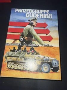 Image of a board game cover titled "PANZERGRUPPE GUDERIAN" featuring an illustration of a military officer looking off into the distance with a stylized background of red stripes and arrows, and a military vehicle with crew members in the foreground. The artist's name R. MacGowan is displayed at the bottom.