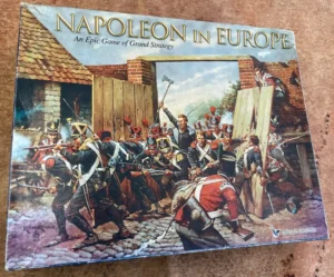 A board game box cover for "NAPOLEON IN EUROPE: An Epic Game of Grand Strategy" featuring a dynamic illustration of Napoleonic-era soldiers in combat by a damaged building, with one soldier prominently leading a charge. The corner of the image shows the logo of Eagle Games and the signature of the artist, "Keith Rocco '96."