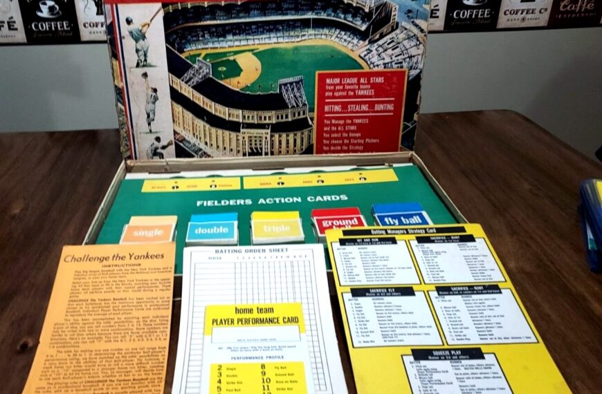 Vintage "Challenge the Yankees" baseball board game displayed open, with game pieces, cards, player performance charts, and game instructions on a tabletop, and the game's box artwork showing a stadium as backdrop.