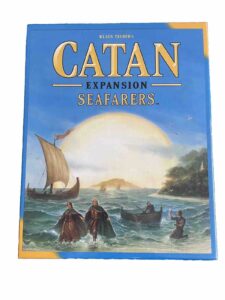 Board game cover for "Klaus Teuber's Catan Expansion: Seafarers" with artwork depicting a sailboat and people in small boats on choppy waters with an island in the background.
