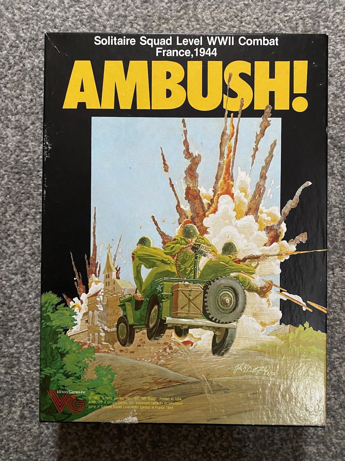 A boxed board game titled "AMBUSH! Solitaire Squad Level WWII Combat France,1944" with artwork depicting a military vehicle and soldiers in an explosion. The Victory Games logo is visible at the bottom left corner.