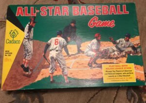The image shows the cover of the "ALL-STAR BASEBALL Game" by Cadaco, featuring illustrated baseball players in action on the field with a vintage design. The cover includes text promoting the game as a way to play ball with major league stars and manage top players, indicating it is a board game for fans of all ages, developed by Ethan Allen. The bottom left corner states it's a "NEW EDITION No. 183" and that it's made in the USA.