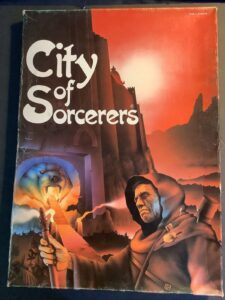 A worn fantasy book cover titled 'City of Sorcerers,' featuring a brooding cloaked figure with a staff in the foreground and a reddish sky over a silhouetted cityscape with towering spires in the background. The cover also notes 'Made in England.'
