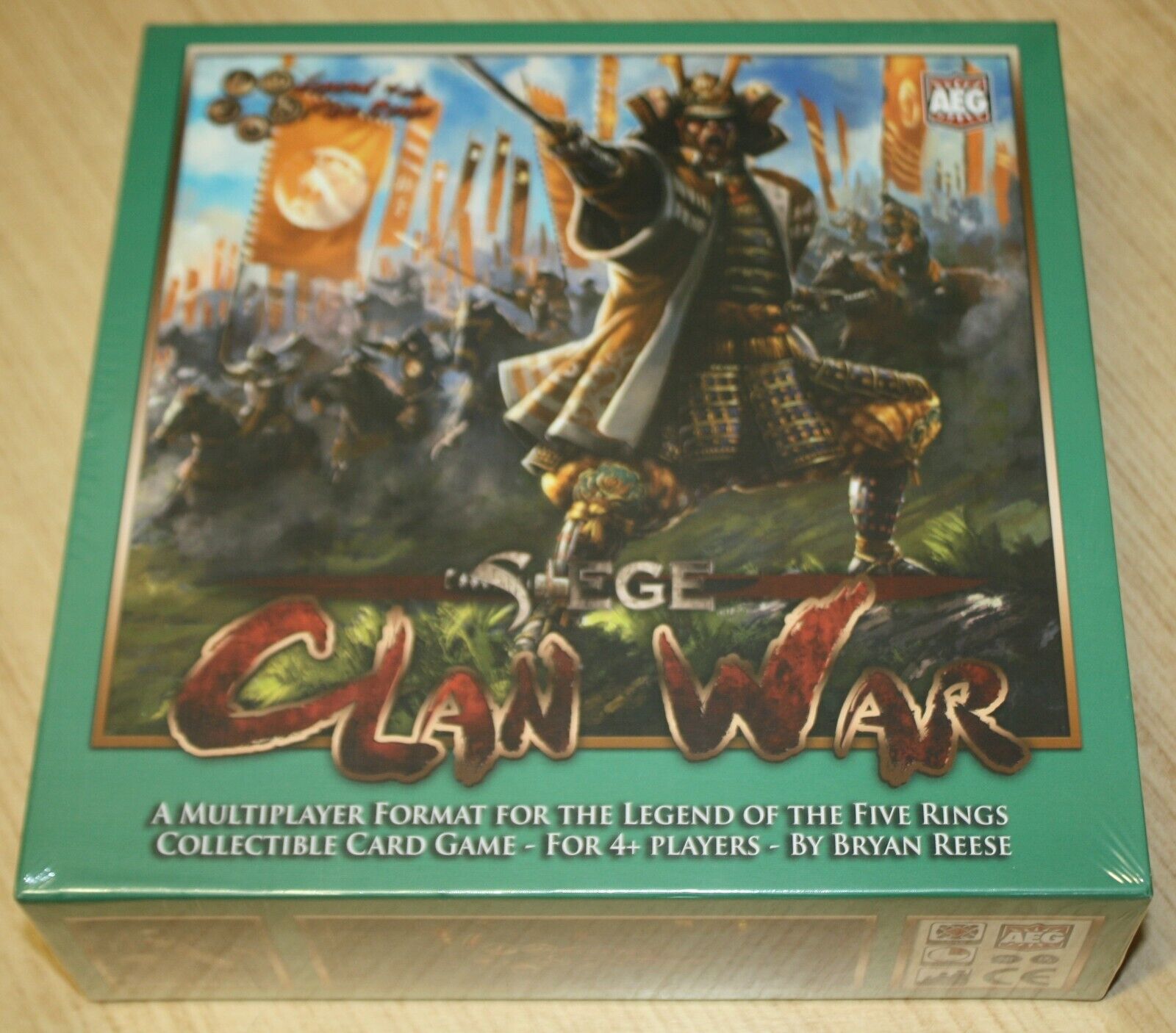 A board game box for "Clan War," a multiplayer format collectible card game for the Legend of the Five Rings, designed for 4+ players by Bryan Reese, featuring artwork of a samurai warrior leading a battle charge on the cover.