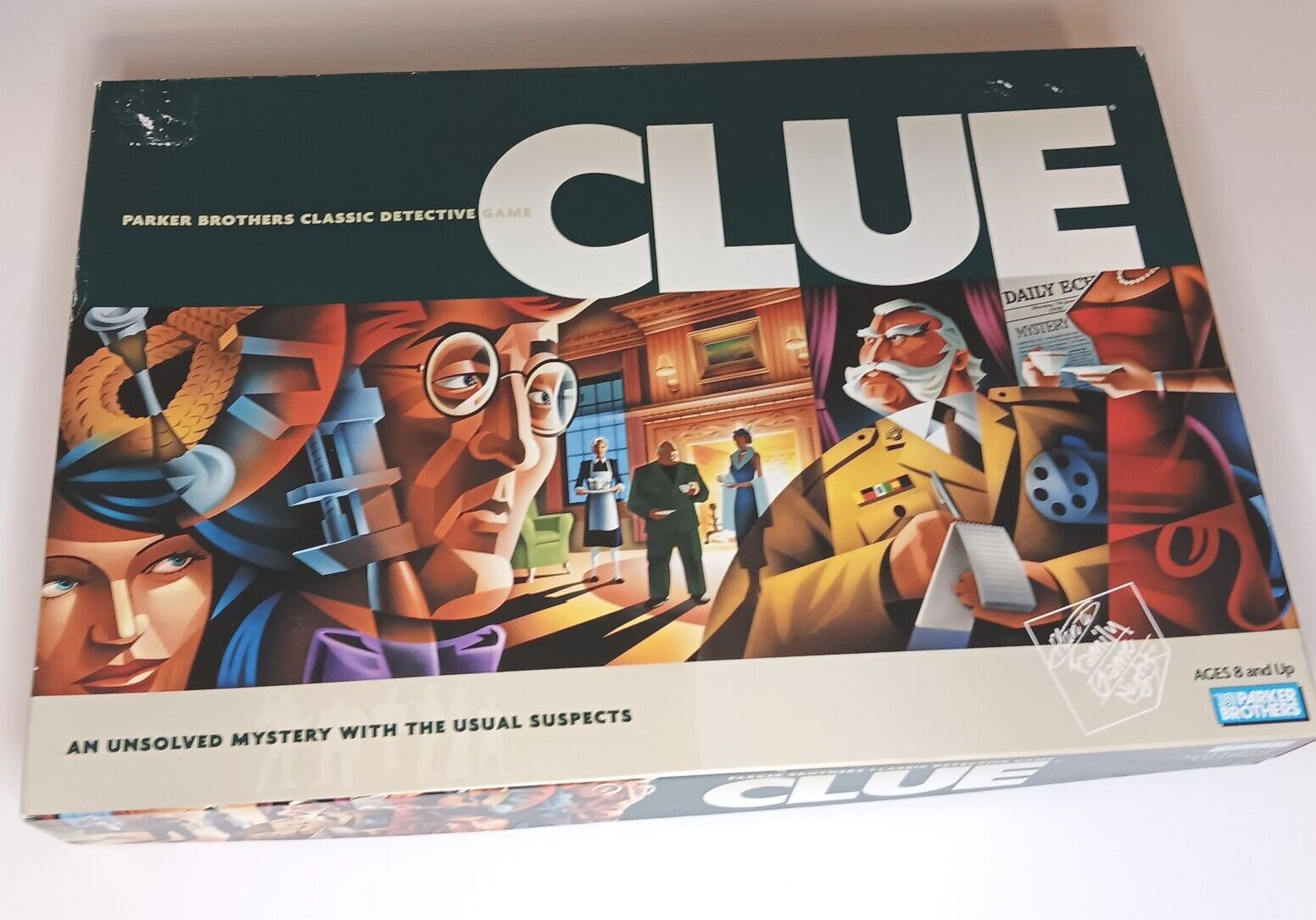 The image shows a box of the board game "Clue" from Parker Brothers, featuring stylized illustrations of classic detective game characters and mystery elements with the tagline "An unsolved mystery with the usual suspects" on the bottom. The game is suitable for ages 8 and up.