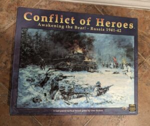 Alt-text: "Box cover for 'Conflict of Heroes: Awakening the Bear! - Russia 1941-42,' depicting a WWII battle scene with soldiers in snow, a burning tank, and trees in the background."