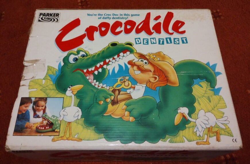 A damaged game box for "Crocodile Dentist" by Parker, featuring an illustration of a cartoon crocodile being treated by a dentist, with a whimsical jungle background and a small photo of two children playing the game in the corner.