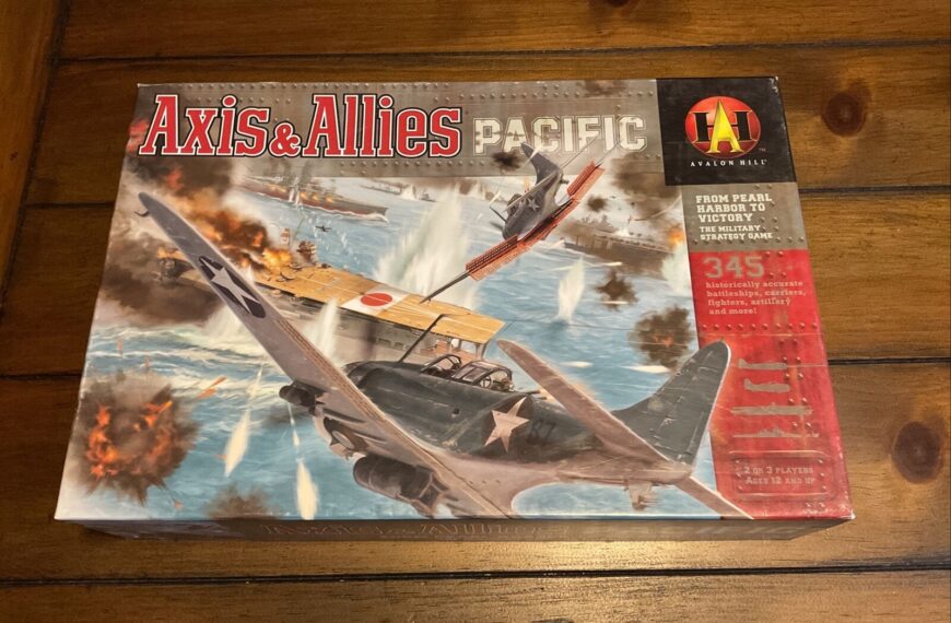 A board game titled "Axis & Allies Pacific" by Avalon Hill, depicting World War II imagery with planes, ships, and explosions, lying on a wooden surface.