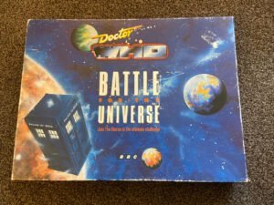 The image shows the cover of a "Doctor Who: Battle for the Universe" board game with a cosmic background featuring stars, nebulae, and planets, and an illustration of the TARDIS. The BBC logo is displayed at the bottom right.