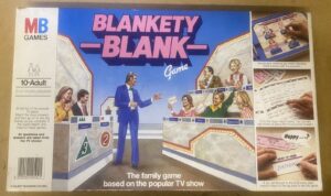 Box cover of the "Blankety Blank" board game featuring illustrated images of a game show setup with a host and contestants, along with images of game components and playing cards, and descriptive text about the gameplay.