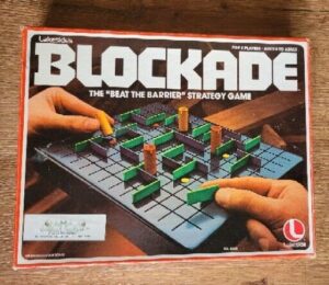 Vintage Blockade board game box with a close-up of a hand playing the strategy game, featuring various colored blocks on a grid.