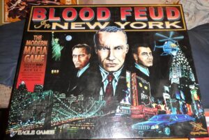 Board game cover art for "Blood Feud in New York" featuring a nighttime scene with illustrated mobster characters, a helicopter, limousine, and New York City skyline with the Statue of Liberty. Text highlights the game's aim and includes phrases such as "The Modern Mafia Game" and "Over 300 Pieces". The game is for ages 12 and up and is produced by Eagle Games.