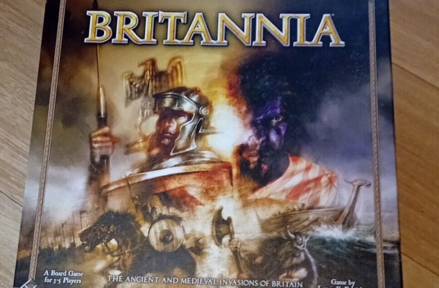 A board game titled "Britannia" placed on a wooden floor, featuring an illustration of historical warriors and a boat, indicating a theme of historical conflict in Britain.