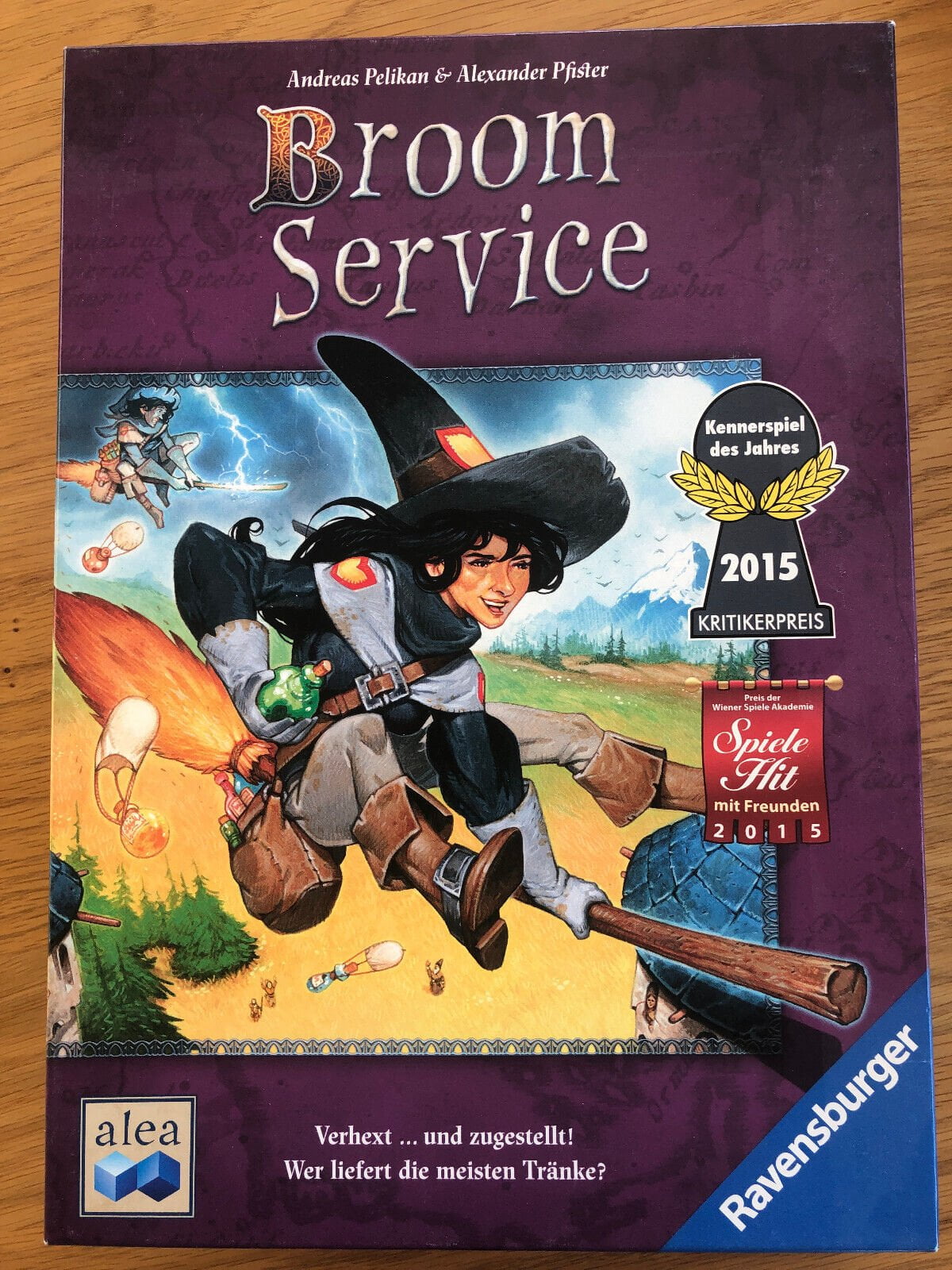 "Broom Service" board game box by Andreas Pelikan & Alexander Pfister, featuring vivid illustration of a witch on a broomstick and a potion being dropped, with the Kennerspiel des Jahres 2015 award, and logos for Ravensburger and Alea.