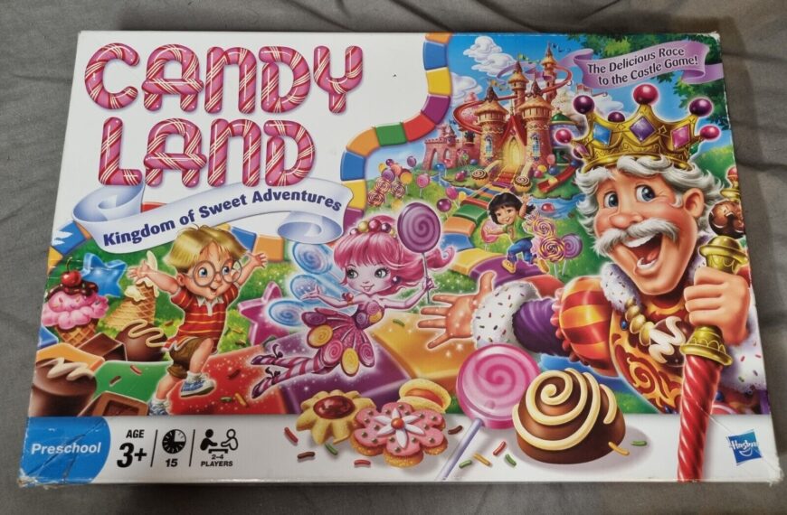 A "Candy Land" board game box featuring cartoon characters, a colorful candy-themed path, a lollipop forest, and a castle in the background. The text on the box reads "Kingdom of Sweet Adventures" and "The Delicious Race to the Castle Game!" Age recommendation is 3+, for 2-4 players, by Hasbro.
