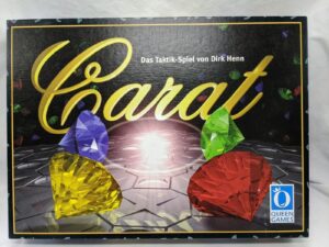 A board game box titled "Karai" from Queen Games, featuring colorful gemstone graphics and text indicating it's a tactical game by Dirk Henn.