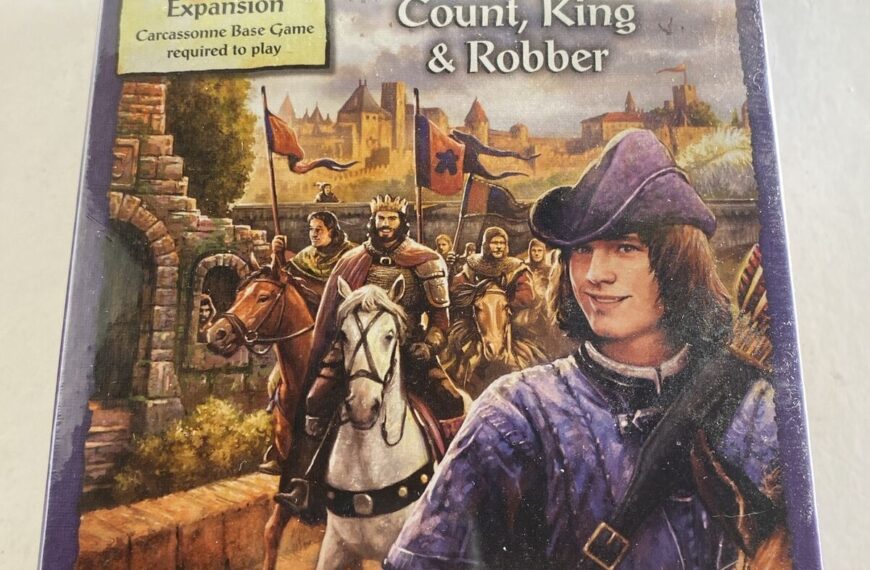 A sealed copy of the board game "Carcassonne Expansion 6: Count, King & Robber" on a tabletop, with artwork depicting medieval characters including a mounted knight and a person in a purple cloak. The text on the cover indicates it is an expansion and requires the Carcassonne base game to play. The game is by Klaus-Jürgen Wrede and published by Z-Man Games.