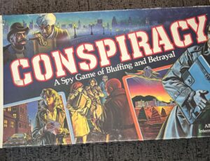 Boardgame cover of "CONSPIRACY: A Spy Game of Bluffing and Betrayal" featuring illustrated spies in various secretive actions, with urban and exotic backdrops.