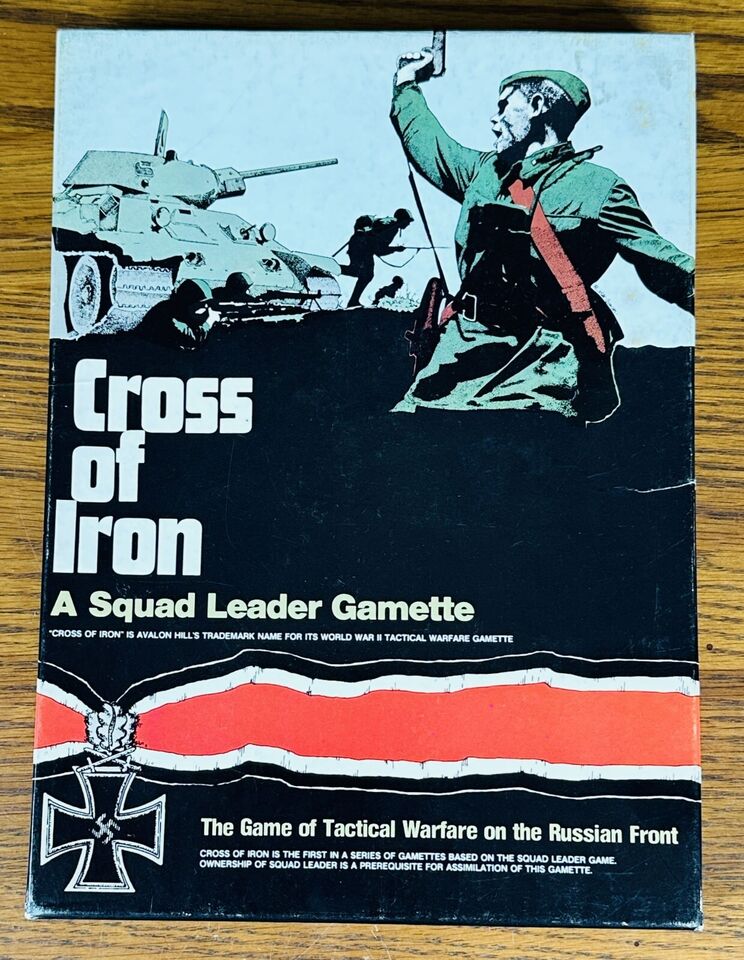 Cover of the "Cross of Iron" squad leader board game, featuring a stylized illustration of a soldier with raised fist in front of a tank and infantry, with the Iron Cross medal and a red and black stripe design on the lower part of the cover.