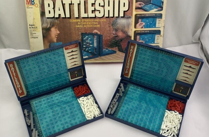 A vintage Battleship board game with its box in the background, and two foldable game boards open in the foreground showing blue grids and compartments with white and red pegs and miniature ship pieces.