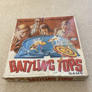 A vintage "Battling Tops" board game box with an illustrated image of excited children and a man watching tops spin in an arena, with the text "Be a Champion in the Bout of the Century!" and the Ideal Toy Company logo.