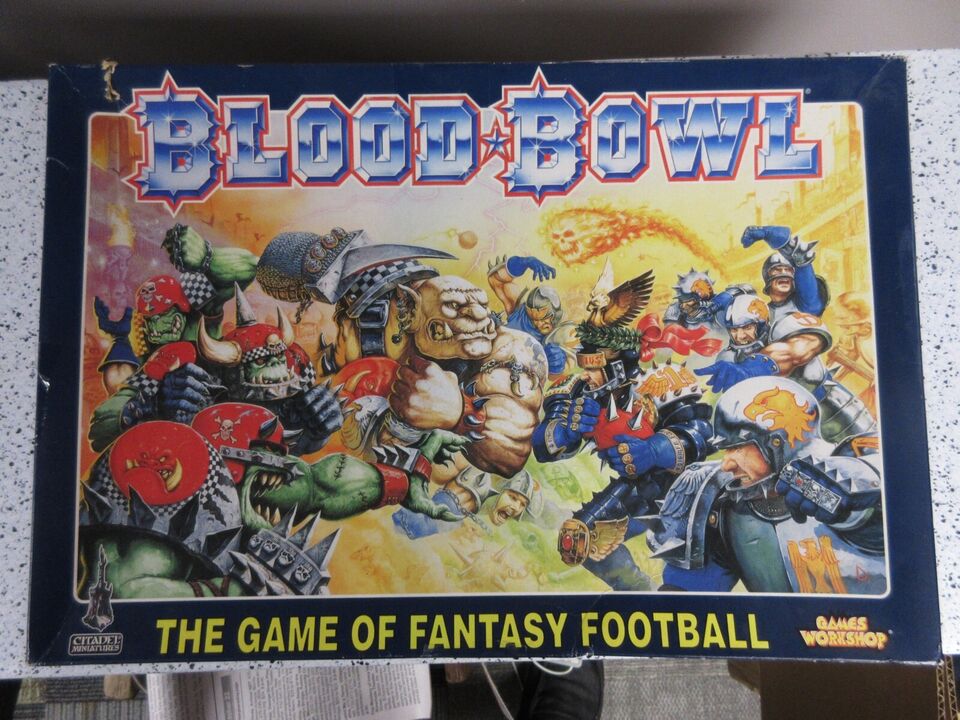 Box art for Blood Bowl, the game of fantasy football, featuring a chaotic illustration of various fantastical creatures and humanoids engaged in a football-like game, with the title in bold red and blue at the top.