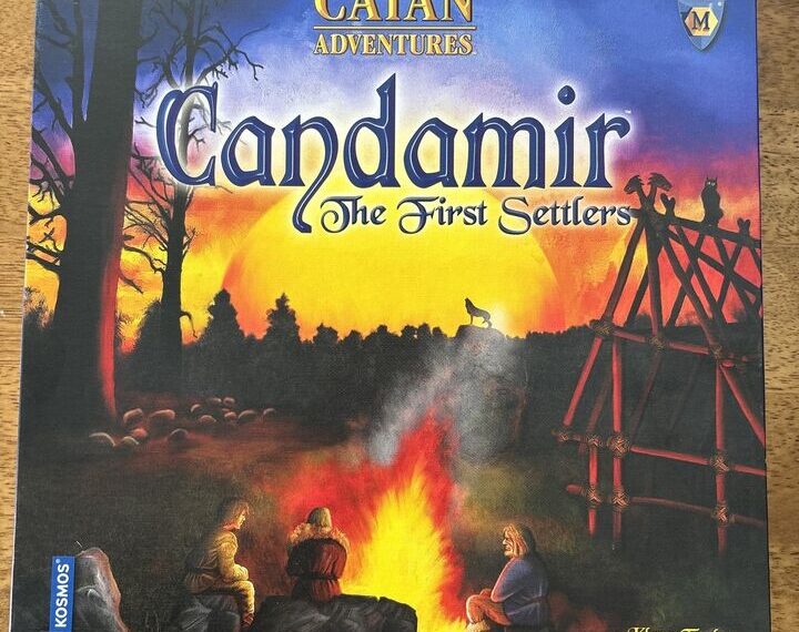 Board game box for "Catan Adventures: Candamir – The First Settlers" depicting a twilight scene with silhouetted trees, settlers around a campfire, and a partially constructed wooden structure against an orange sky. The Kosmos logo is in the bottom left corner and the designer's name, Klaus Teuber, is at the bottom right.