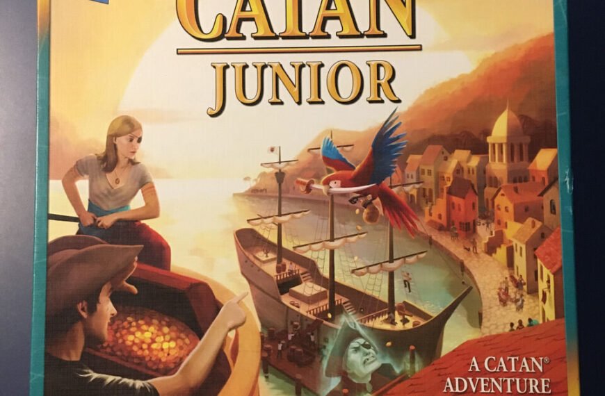 Box cover for the "CATAN Junior" board game showing a boy and a girl looking out to sea with a parrot flying overhead, a harbor scene with ships in the background, and text describing it as "A CATAN Adventure for Fledgling Swashbucklers."