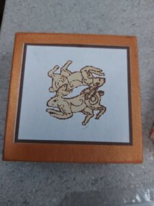 A laser-engraved image of a scorpion on a white background, framed with a brown border and housed in a light brown frame.