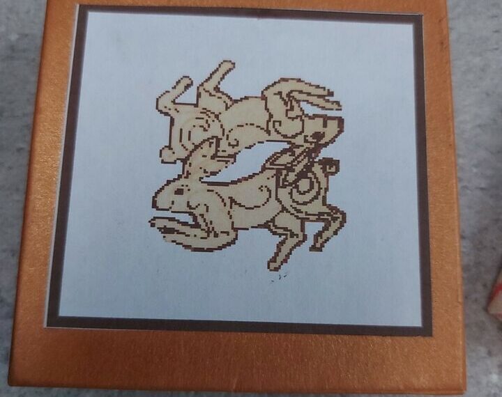 A laser-engraved image of a scorpion on a white background, framed with a brown border and housed in a light brown frame.