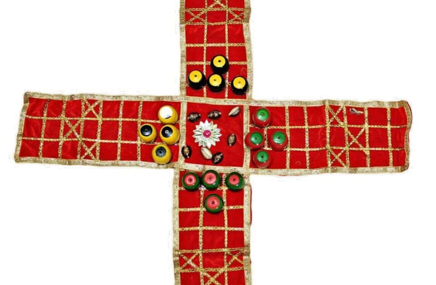 A handmade cross with a red fabric background embellished with a gold grid pattern and decorated with various colorful buttons and beads.