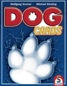 Cover of "Dog Cards" game featuring a large, white paw print on a blue cracked glass background, with the game's title in bold red and yellow letters, and names Wolfgang Kramer and Michael Kiesling at the top.